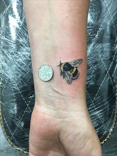 a small tattoo on the wrist of a person with a bee on it's arm