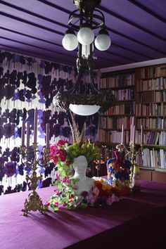 an image of a table with flowers and candles on it in front of bookshelves