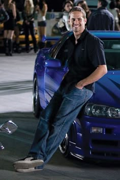 a man sitting on the hood of a blue car