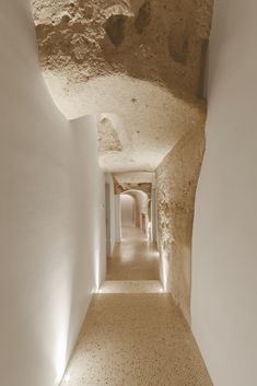 the narrow hallway is lined with white walls and stone steps that lead up to two rooms