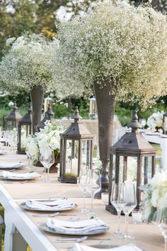 an outdoor table set with white flowers and candles