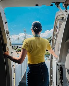 a woman in yellow shirt opening the door to an airplane