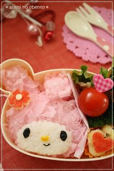 a hello kitty bento box filled with sushi and veggies on a table