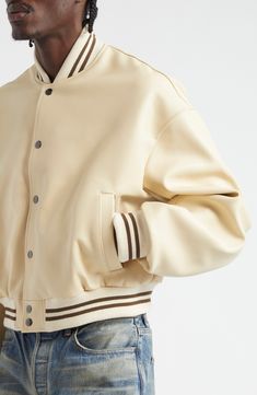 The label draws inspiration from traditional sporting aesthetics with a varsity-style bomber jacket crafted from smooth, buttery-soft leather. 22" length (size Large) Front snap closure Blade collar Front welt pockets Ribbed cuffs and hem Lined Leather with cotton/polyester trim Professional leather clean Made in the USA Designer Clothing Sporty Beige Outerwear With Ribbed Cuffs, Beige Sporty Outerwear With Ribbed Cuffs, White Varsity Jacket With Ribbed Collar For College, White Sporty Varsity Jacket With Ribbed Collar, White Leather Streetwear Outerwear, White Leather Streetwear Jacket, Leather Outerwear With Ribbed Collar For Streetwear, White Leather Outerwear For Streetwear, Leather Outerwear With Baseball Collar For College