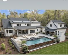 an aerial view of a large house with a pool in the yard and landscaping around it