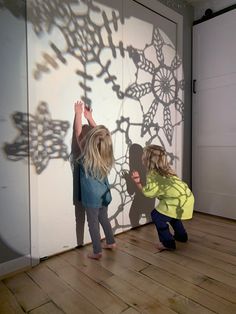 two children are playing with shadows on the wall