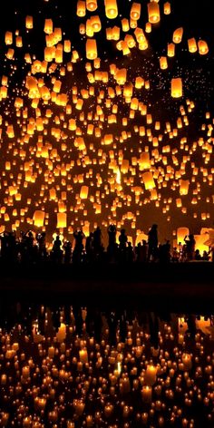 many lit up lanterns floating in the air