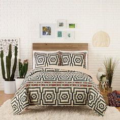 a bed with a black and white bedspread next to potted cacti