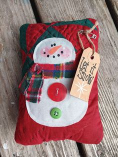 a snowman ornament with a tag on it sitting on a wooden bench