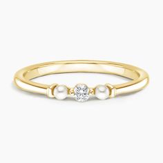 a yellow gold ring with two pearls and a single diamond in the middle, on a white background