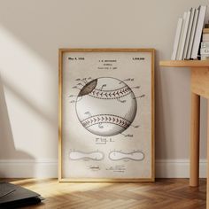 a framed baseball diagram on a wall next to a wooden table with books and a laptop