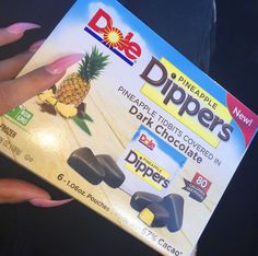 someone holding up a box of dippers with pineapple and chocolate in it's wrapper