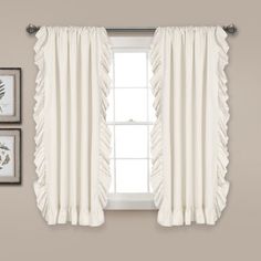 white curtains hanging on the side of a wall next to two framed pictures and a window