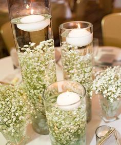 three vases with flowers and candles on a table