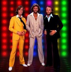 three men in suits and ties standing next to each other on a stage with colorful lights behind them