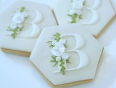 three decorated cookies with white frosting and green leaves are arranged in the shape of hexagons