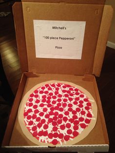 a box with a pizza inside of it on a table next to a sign that says michel's 10 piece pepperoni