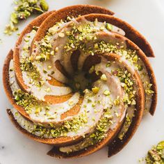 a white plate topped with cake covered in frosting and pistachio toppings