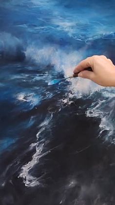 a hand reaching for something in the ocean with blue water and white foamy waves