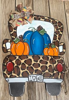 an animal print car with pumpkins and leopard spots on the hood, sitting on a wooden surface