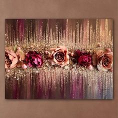 an abstract painting with pink roses and gold sequins on the bottom, in front of a brown wall