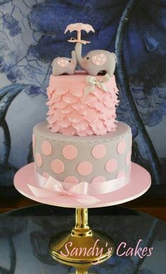 a pink and gray cake with polka dots on it sitting on top of a table