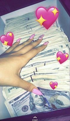 a person's hand with pink nails and hearts on top of stacks of money