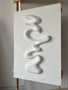 a white sculpture sitting on top of a wooden easel