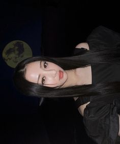 a woman with long black hair posing for the camera