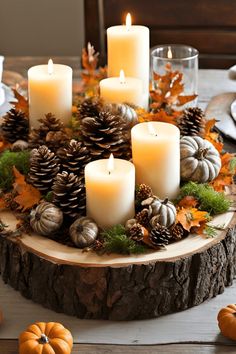 a table topped with lots of candles next to pumpkins and pineconuts on top of a wooden slice