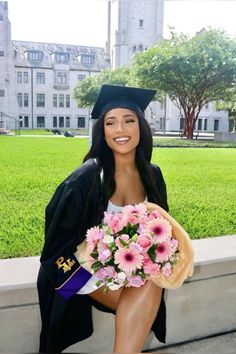 a woman in graduation cap and gown sitting on a bench with flowers next to her