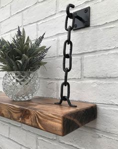 a potted plant sitting on top of a wooden shelf next to a metal chain