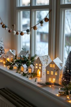 a window sill decorated with christmas lights and small houses on top of the windowsill