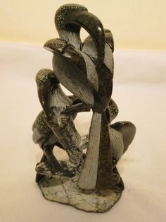 two birds sitting on top of each other in the shape of a sculpture with their beaks open