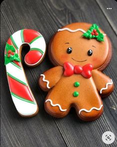 two decorated gingerbread cookies sitting next to each other on a wooden table with candy canes