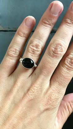 This oval black onyx stone is set in sterling silver with two sterling silver accent balls on either side. The oval cabochon is about 1/2" wide or 12mm x 10mm. The ring band is made from flat rectangular sterling silver wire. This ring is elegant and lovely.Made to order, choose your size! Black Oval Cabochon Sterling Silver Jewelry, Black Sterling Silver Jewelry With Oval Cabochon, Black Cabochon Sterling Silver Ring, Black Sterling Silver Cabochon Ring, Boho Rocker, Mens Ring Designs, Black Onyx Stone, Black Onyx Ring, Onyx Ring