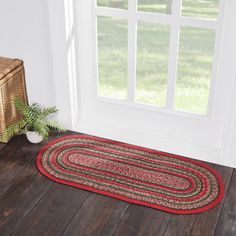 a red and black area rug sitting on top of a wooden floor next to a window