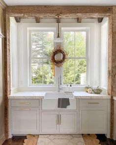 a kitchen with white cabinets and a wreath on the window sill above the sink