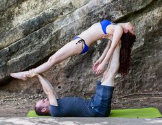 a man and woman are doing yoga in front of a rock face - to - face