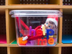 an elf in a plastic container with the word help me spelled out on it's side