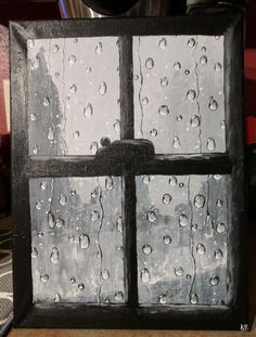 a window with rain drops on it in front of a potted plant and other items