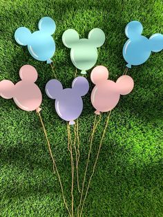 four mickey mouse balloons in the grass with one balloon stuck to it's head