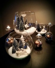 there are several glass vases with christmas trees in them and snow on the ground