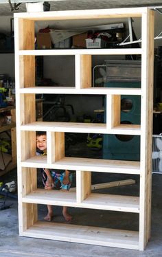 a young boy standing in front of a wooden book shelf with shelves on each side