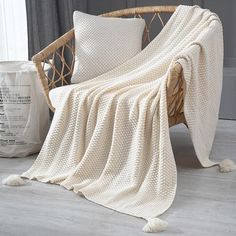 a white blanket sitting on top of a wicker chair