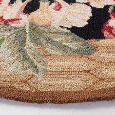 an area rug with flowers and leaves on the bottom is laying on top of a white surface