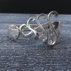 a silver ring with an ornate design on it's side, sitting on top of a wooden table