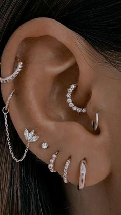 a close up of a person with ear piercings and chains on their ears,