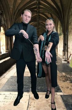 a man and woman standing next to each other in an old building with stone floors