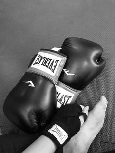 a pair of black boxing gloves sitting on top of a person's hand in front of a punching mitt